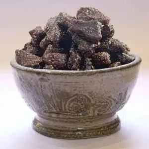 Dark glossy chocolate brittle chunks piled in a rustic ceramic bowl.